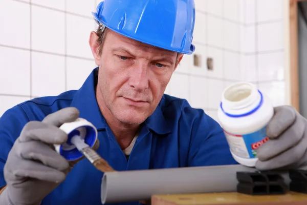 Plumber carefully gluing plastic pipe — Stockfoto