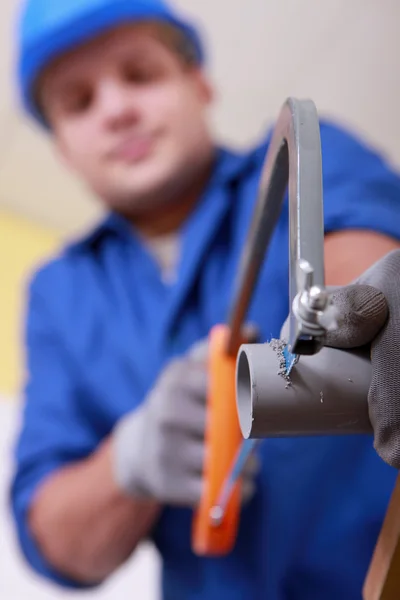 Plumber sawing plastic pipe — Stock Photo, Image