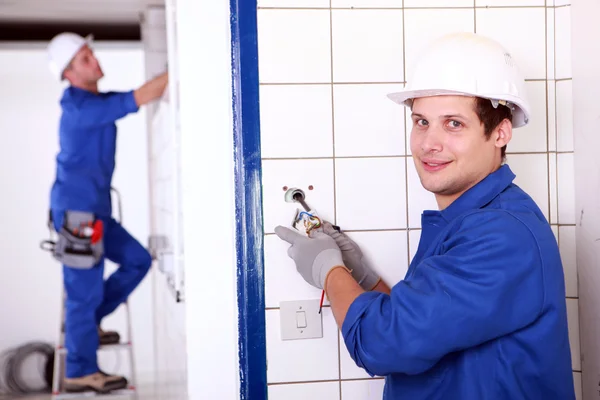 Two electrician fixing electrics in bathroom — Stock Photo, Image