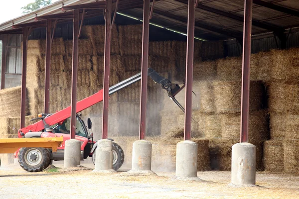 Farm vehicle lifting bails of hay — Stock Photo, Image