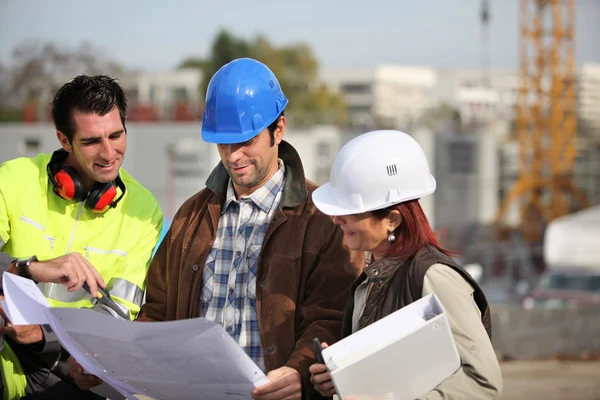 Foreman e dois colegas examinando planos — Fotografia de Stock