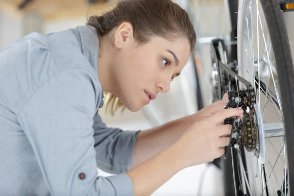 女性机修工车间安装或修理自行车轮 — 图库照片