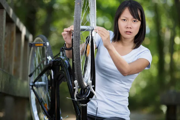 女性は公園内の電動自転車を修理しています ストック画像