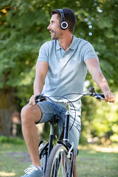 森の中でヘッドフォンをして自転車に乗る若いスポーツマン — ストック写真