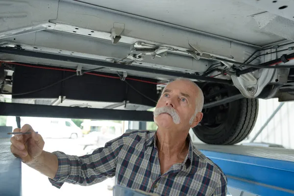 Männlicher Senior Arbeitet Unter Einem Angehobenen Auto — Stockfoto