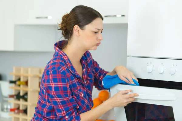 年轻快乐的女人在打扫烤箱 — 图库照片