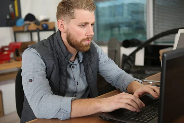 Νεαρός Άνδρας Που Χρησιμοποιεί Φορητό Υπολογιστή Στο Βιομηχανικό Γραφείο — Φωτογραφία Αρχείου