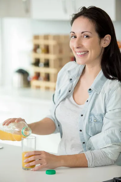 Vrouw Thuis Schenkt Een Glas Sinaasappelsap — Stockfoto