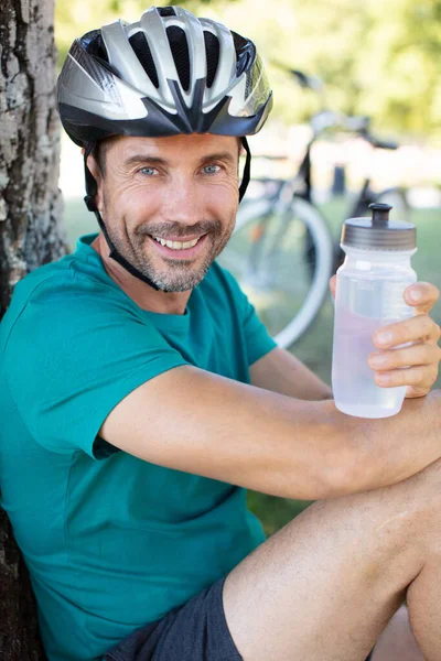 快乐的笑着骑自行车的人一边喝水一边休息 — 图库照片