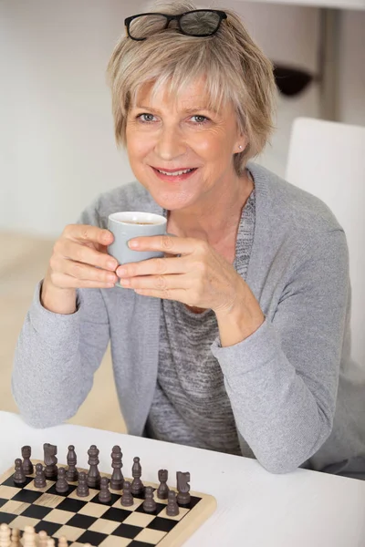 Feliz Mulher Sênior Tomando Café Enquanto Joga Xadrez — Fotografia de Stock