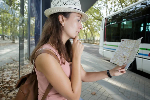 妇女在巴士站等候时正在看地图 — 图库照片