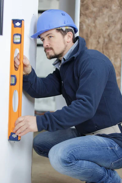 Worker Blue Uniform Measures Wall Level — Stock Photo, Image