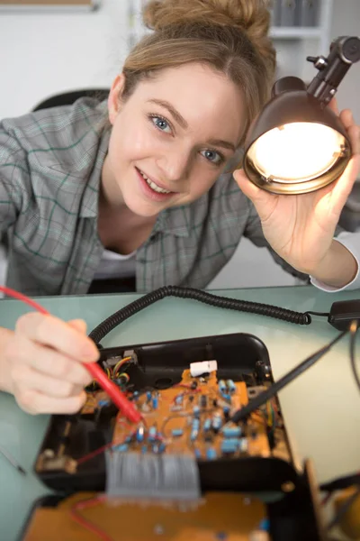 Mujer Joven Con Overoles Que Fijan Dispositivo Electrónico —  Fotos de Stock