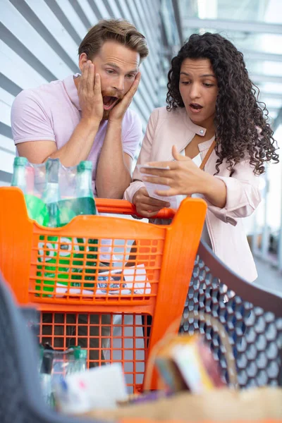 Giovane Coppia Stupita Controllando Una Lunga Ricevuta Della Spesa Supermercato — Foto Stock