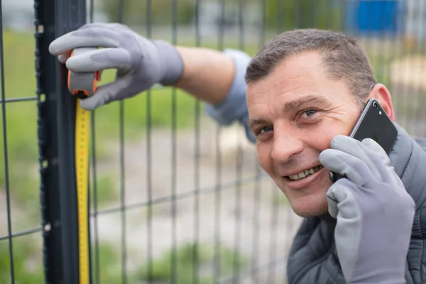 Glücklicher Mann Telefon Der Einen Zaun Baut — Stockfoto