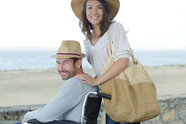 海の近くで遊んでいる妻を持つ障害者は — ストック写真