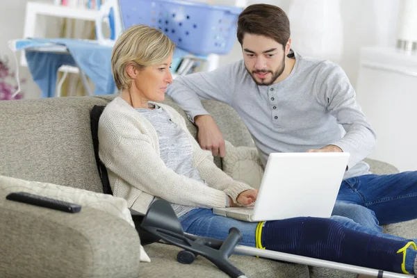 Ung Man Hjälpa Kvinna Med Benskador Att Använda Laptop — Stockfoto