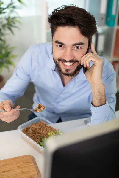 Άνθρωπος Τρώει Ενώ Εργάζεται Στο Τηλέφωνο — Φωτογραφία Αρχείου