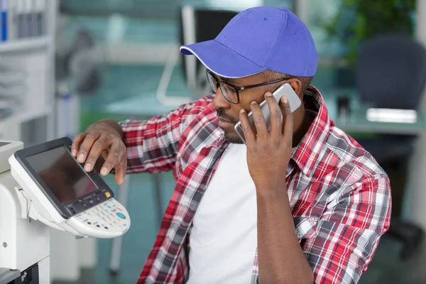 technician seeking help on the phone while repairing printer