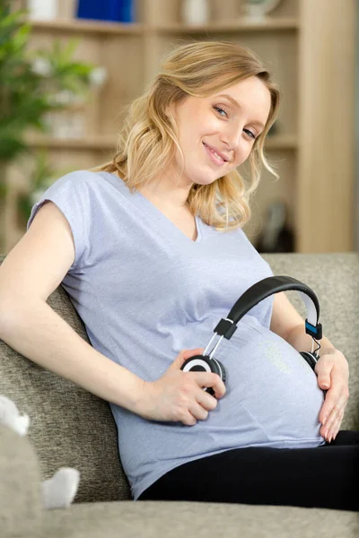 在怀孕的肚子上关上耳机 — 图库照片