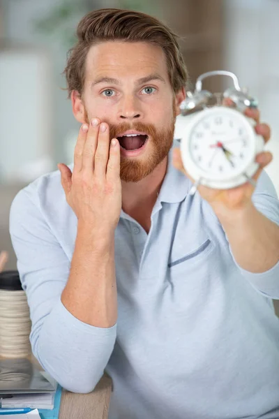 Шокований Молодий Бізнесмен Своїм Столом Тримає Годинник — стокове фото