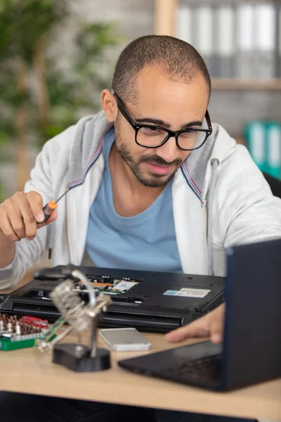 若いエネルギッシュな男性技術者がラップトップを修理 — ストック写真