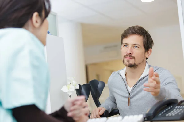 Réceptionniste Parlant Patient Masculin Dans Une Clinique — Photo