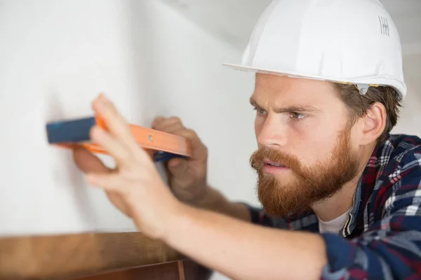 Frunciendo Ceño Constructor Sosteniendo Nivel Espíritu Contra Pared — Foto de Stock