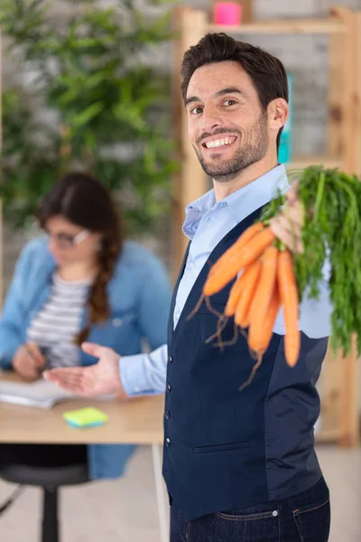 Χαρούμενος Άνθρωπος Δείχνει Καρότα Στο Γραφείο — Φωτογραφία Αρχείου