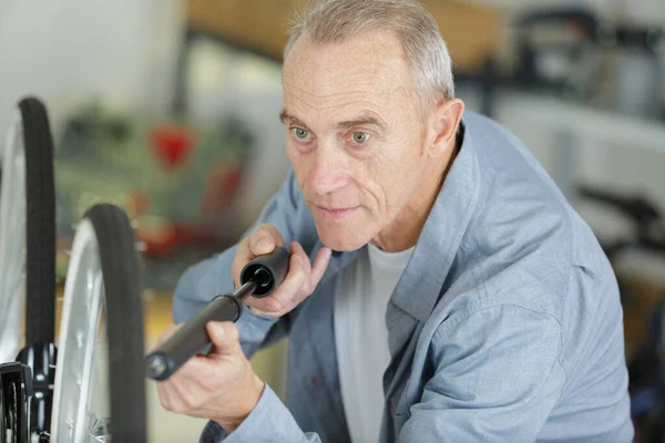 Senior Man Pompt Een Fiets Wiel — Stockfoto