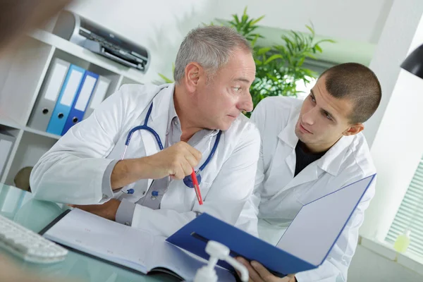 Medico Che Controlla Cartelle Cliniche Con Assistente — Foto Stock