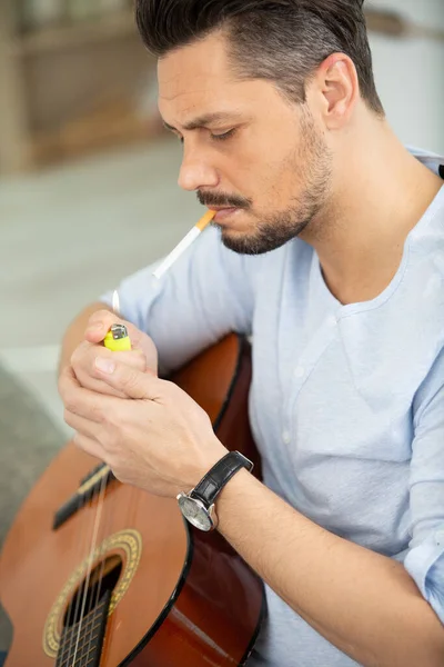 Een Man Rookt Terwijl Hij Gitaar Speelt — Stockfoto