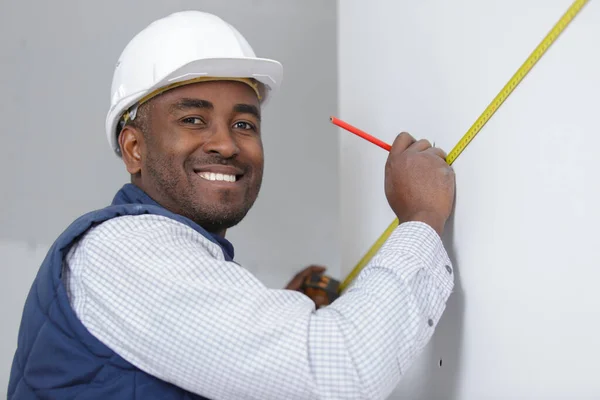 Hombre Feliz Mide Pared Con Una Regla —  Fotos de Stock