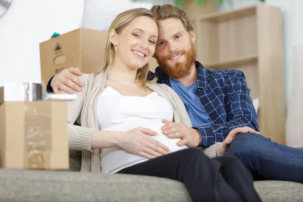 在沙发上放盒子的怀孕夫妇 — 图库照片