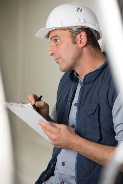 Contemplatieve Werkman Die Een Klembord Vasthoudt — Stockfoto