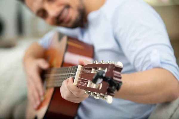 Jovem Bonito Tocando Guitarra Enquanto Sentado Sofá — Fotografia de Stock
