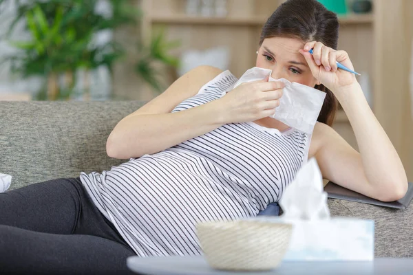 Schwangere Auf Sofa Hält Thermometer Und Pustet Sich Die Nase — Stockfoto