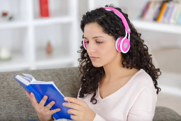 Γυναίκα Που Φοράει Ακουστικά Και Βιβλίο Ανάγνωσης Στο Σπίτι — Φωτογραφία Αρχείου