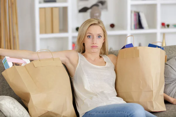 疲倦的女士拿着一袋袋食品坐在沙发上 — 图库照片