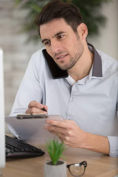 Schöner Geschäftsmann Macht Sich Notizen Während Telefoniert — Stockfoto