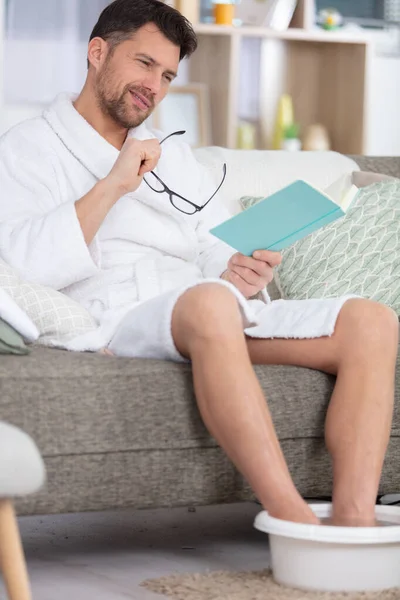 Junger Mann Liest Ein Buch Während Ein Fußbad Nimmt — Stockfoto