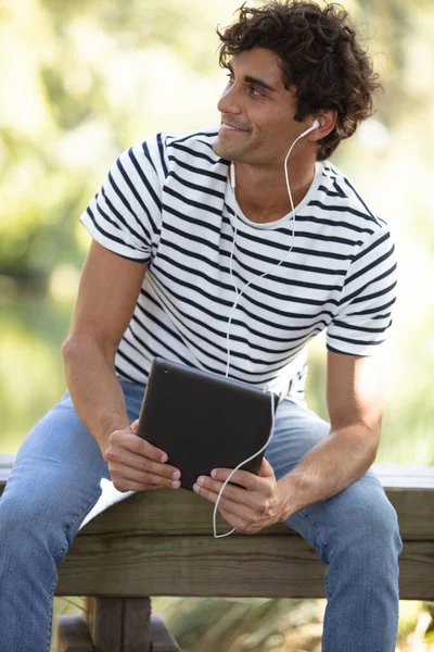 Młody Mężczyzna Siedzący Zewnątrz Słuchanie Muzyki — Zdjęcie stockowe