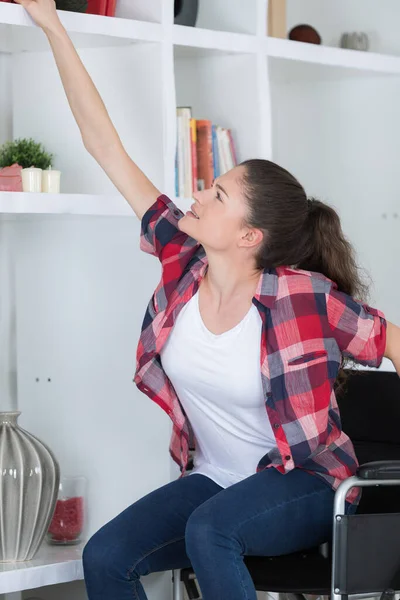 Rolstoel Boung Meisje Grijpen Voor Boek Van Hoge Plank — Stockfoto