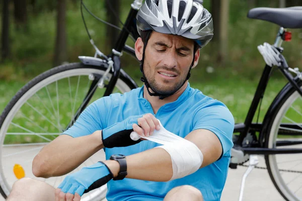 負傷した肘を包む男性サイクリストは — ストック写真