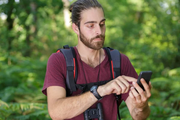 森林里的男性徒步旅行者使用手机 — 图库照片