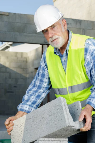 Construtor Envelhecido Vestindo Hardhat Branco Que Estabelece Blocos Parede Concreto — Fotografia de Stock