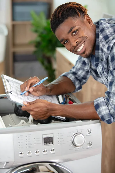 Man Serviceagent Med Urklipp Genom Demonterad Tvättmaskin — Stockfoto