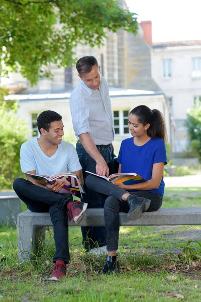 Insegnante Parlando Con Gli Studenti Seduti Sulla Panchina Nel Campus — Foto Stock