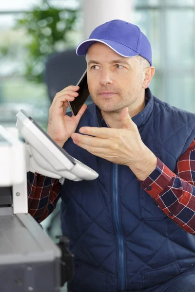 Handyman Fixing Printer While Talking Phone — Stock Photo, Image