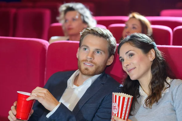 映画館で映画を見ながらポップコーンを持っている若いカップル — ストック写真